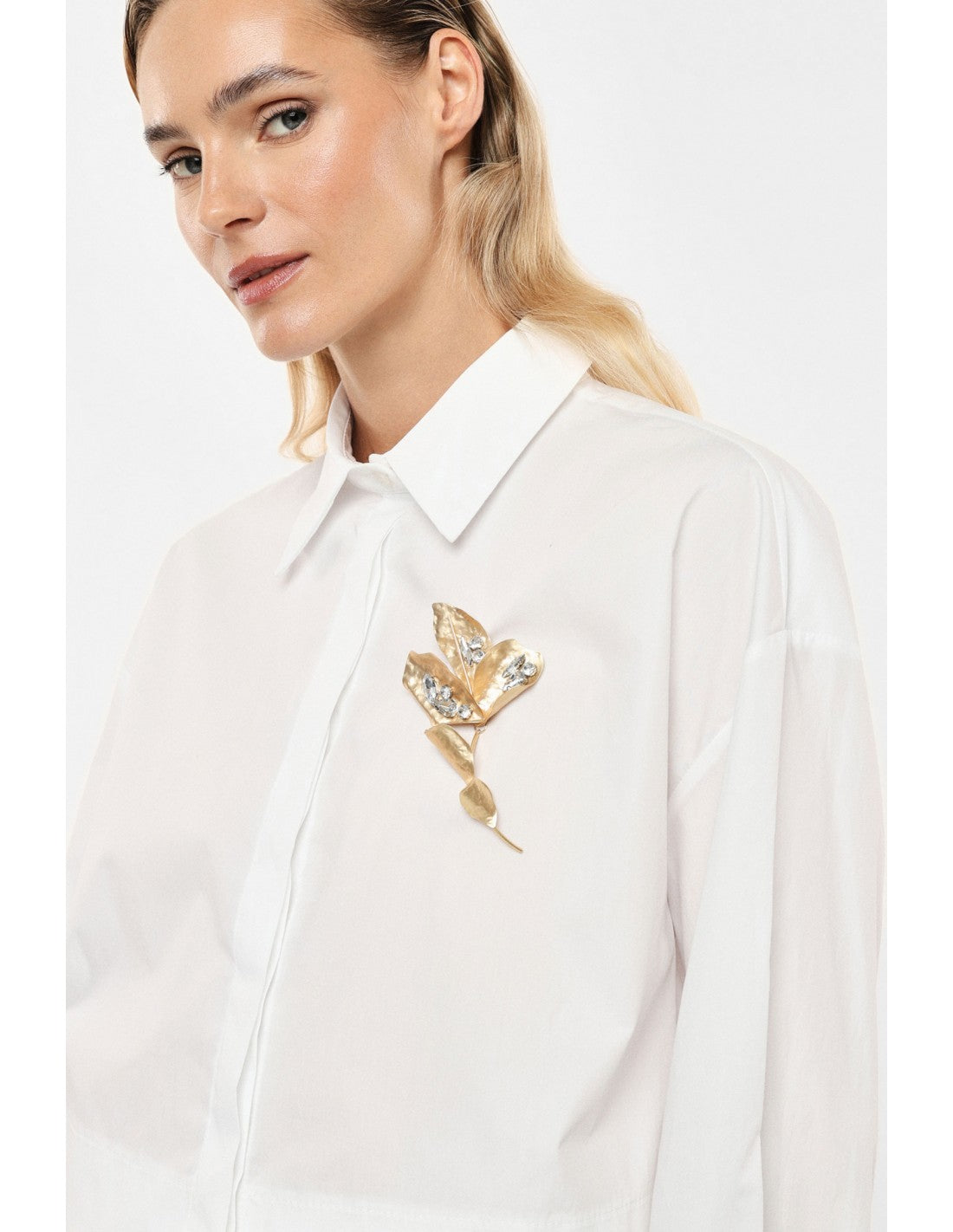 Chemise cropped, détail de la broche bijou dorée sertie de cristaux